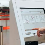 Passageira utiliza um quiosque de autoatendimento em um aeroporto.