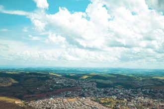 Vista aérea da paisagem de Ouro Branco, em Minas Gerais, com morros sob o céu claro.
