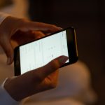 Mãos configurando um alarme em um smartphone, representando o uso de tecnologia para receber lembretes.