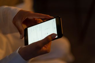 Mãos configurando um alarme em um smartphone, representando o uso de tecnologia para receber lembretes.